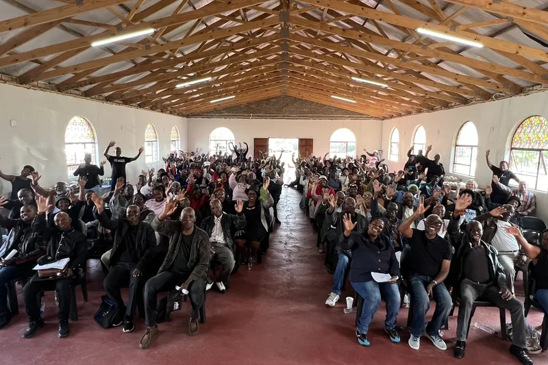 Community members at a broad-based stakeholder meeting in a large hall in South Africa