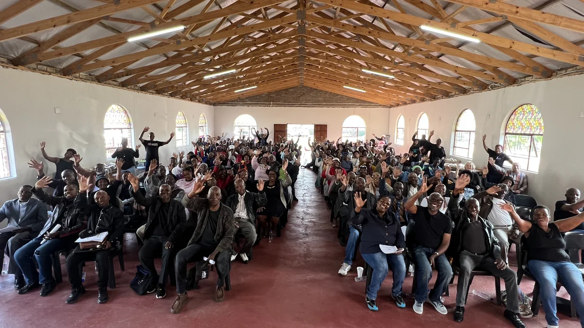 Community members at a broad-based stakeholder meeting filling a large hall in South Africa
