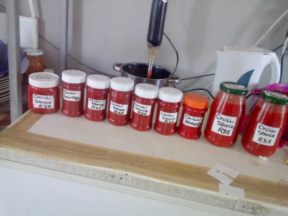 Home-made chilli sauce bottled, labelled and priced for sale, a value-added small business using garden produce