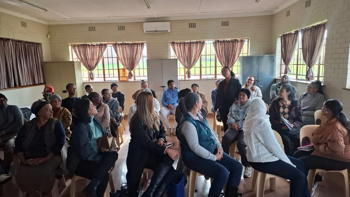 Community stakeholder engagement session in progress, community members and facilitators seated together in a community hall